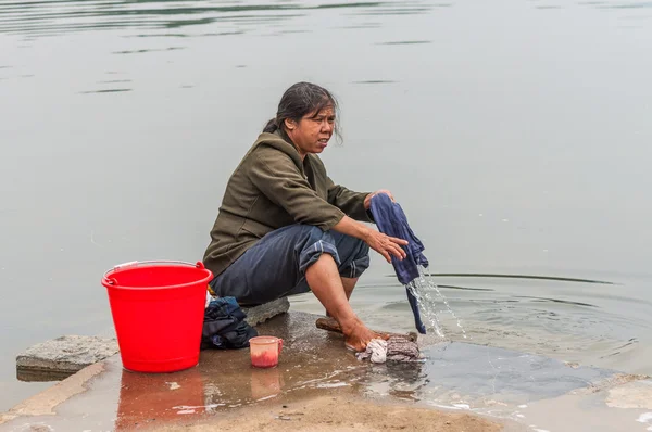 Peasant woman rinse laundry in water river, China