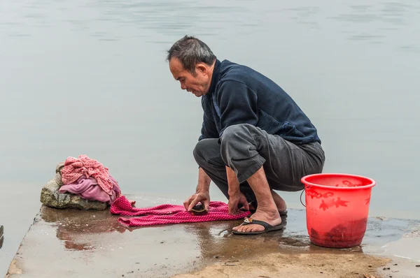 Chinese peasant man washes in the river, China