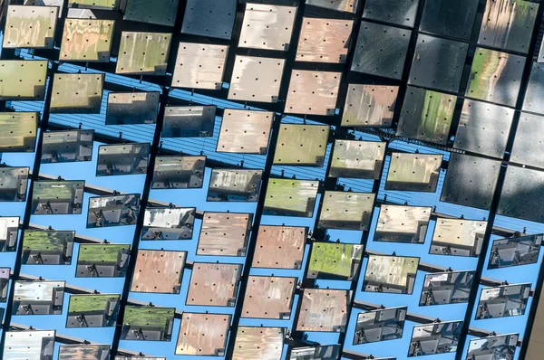 Closeup low angle view of heliostat of motorised mirrors on high rise building Sydney Australia