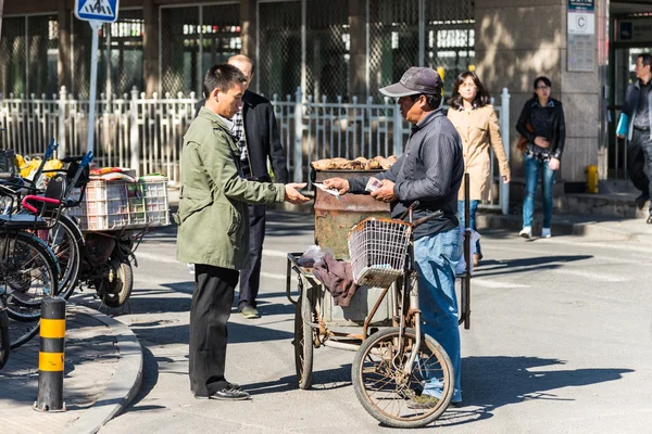 Street vendor selling potatoes to a customer