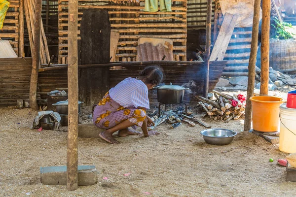 An outdoor kithchen with and old woman cooking food.