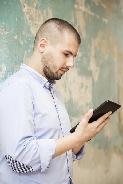 Young man with tablet by the wall