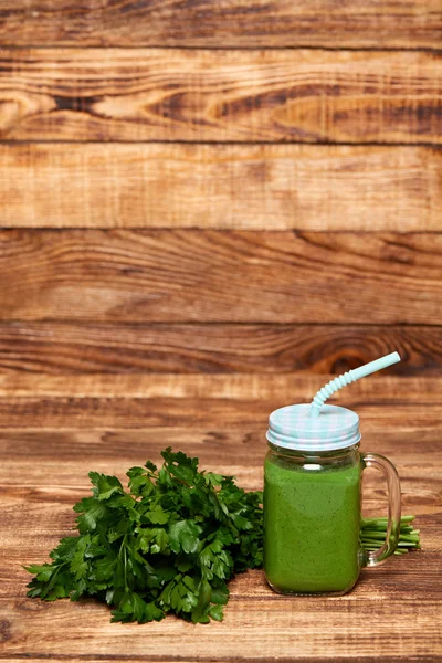 Mug with green smoothie drink and bundle of fresh parsley