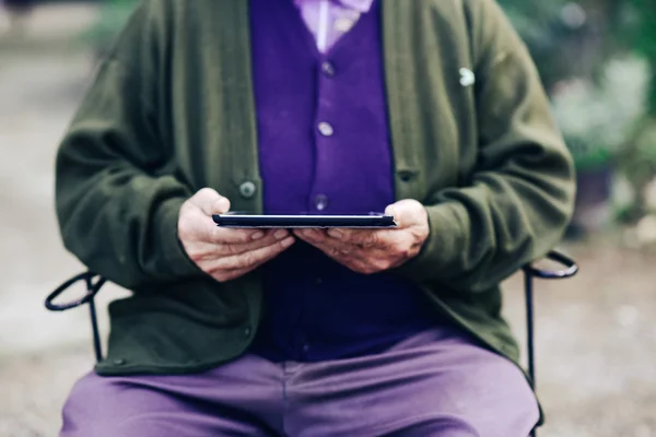 Old man using a tablet computer outdoors
