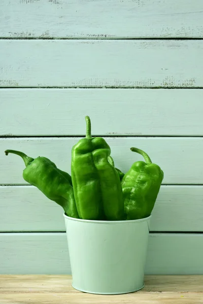 Raw green peppers in a pale green bucket
