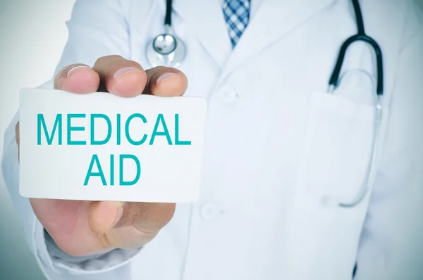 Doctor with a signboard with the text medical aid