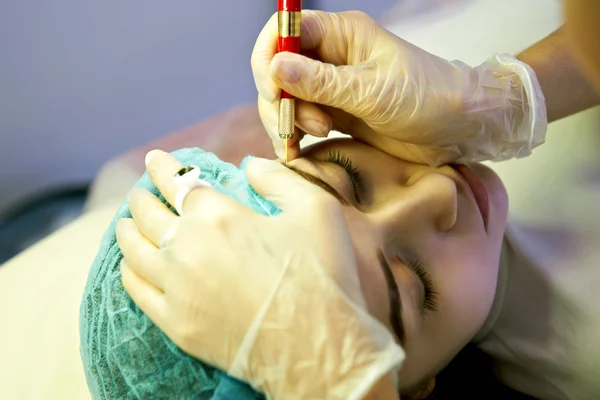 Cosmetician making permanent eyebrow make up