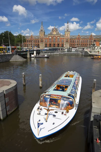 Canal cruise boat in front of amsterdam central railway station