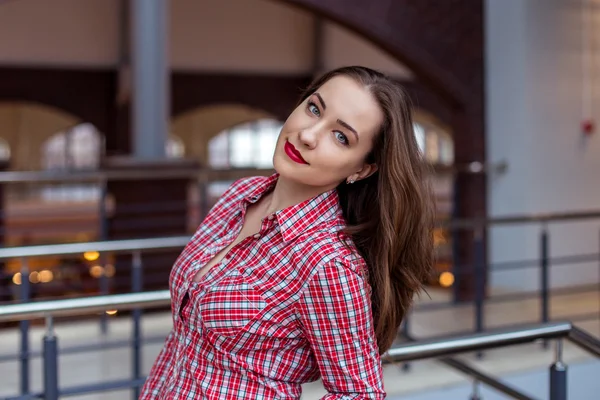 Attractive young woman with long curly hair in checkered shirt
