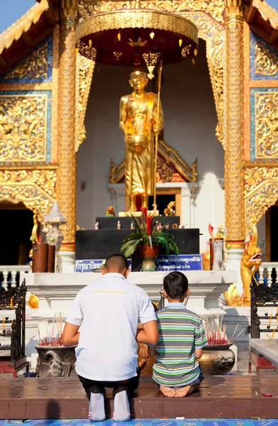 Father and son worshiping Buddha