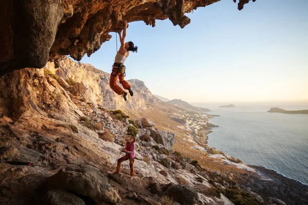Young woman lead climbing on overhanging cliff