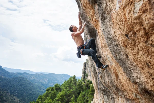 Male rock climber on challenging route on cliff