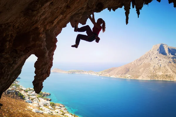 Female rock climber on overhanging cliff