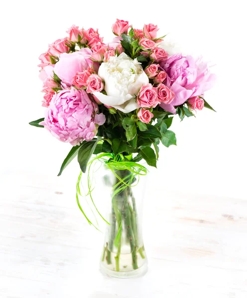 Summer bouquet of peonies in a glass vase on a white wooden tabl