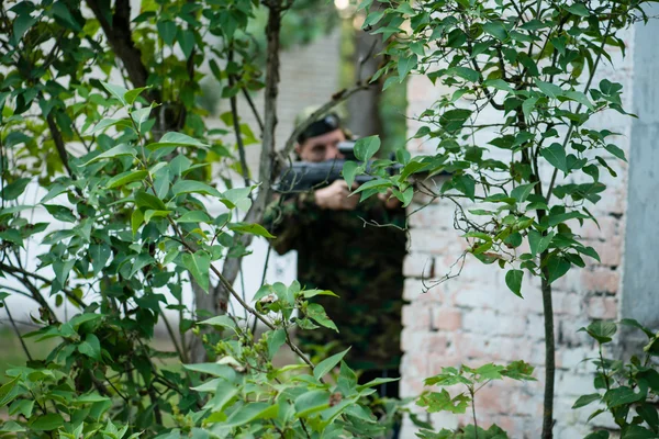 Laser tag game, soldiers with guns blurred behind trees