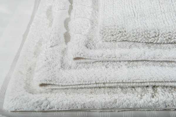 Stack of white bath mats .