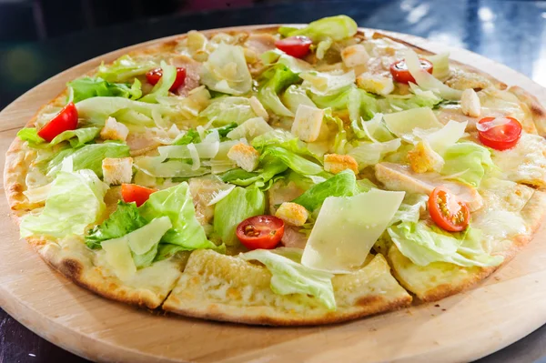 Pizza quattro fromagg topped with fresh saladi on a wooden board