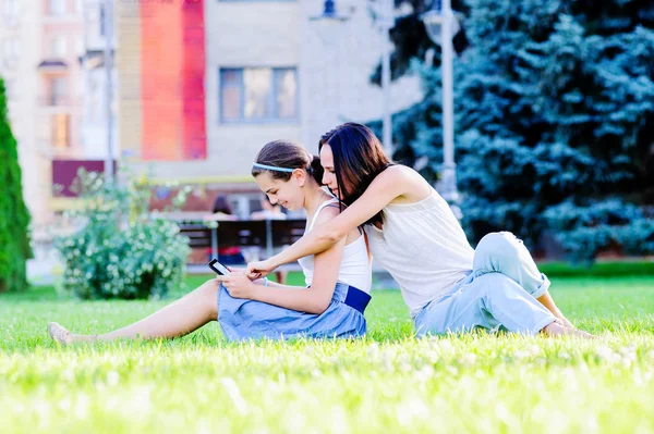 Mother is reading from tablet with her daughter, outdoor shoot