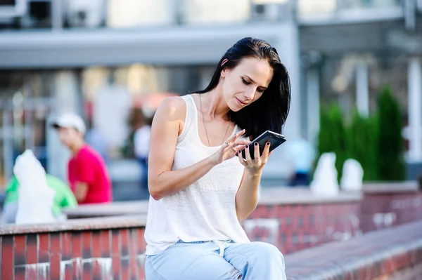 Yang and beautiful modern business woman poses outdoor with smart phone