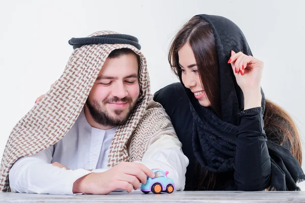 Middle eastern way dressed young couple playing with toy car.