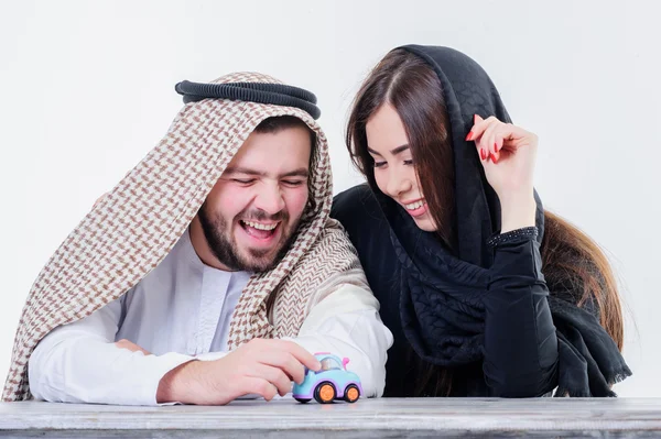 Middle eastern way dressed young couple playing with toy car.