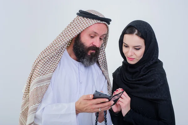 Portrait of Arabic way dressed couple play with mobile phone.