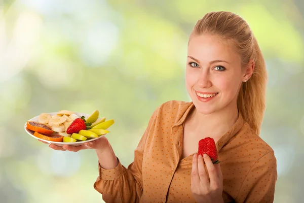 Beautiful young caucasian blonde woman holds a delicious fruit s