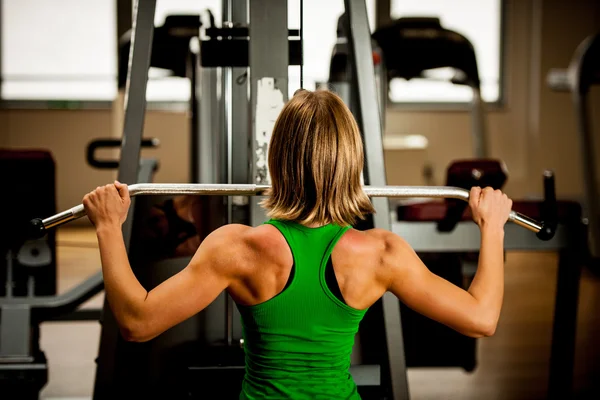 Beautiful muscular fit woman exercising building muscles in fitn