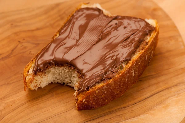 Slice of bread with sweet chocolate nougat spread, bite.