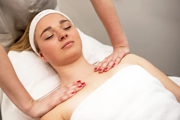 Young woman lying on massage table receiving face massage. Beaut