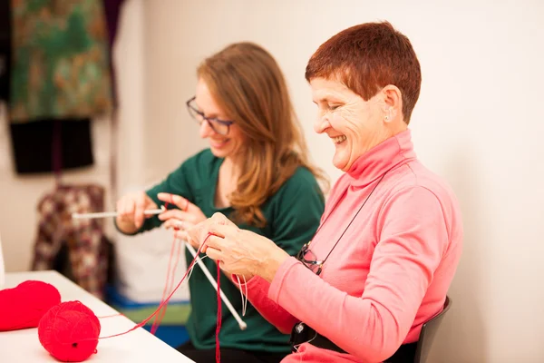 Women knitting with red wool. Eldery woman transfering her knowl