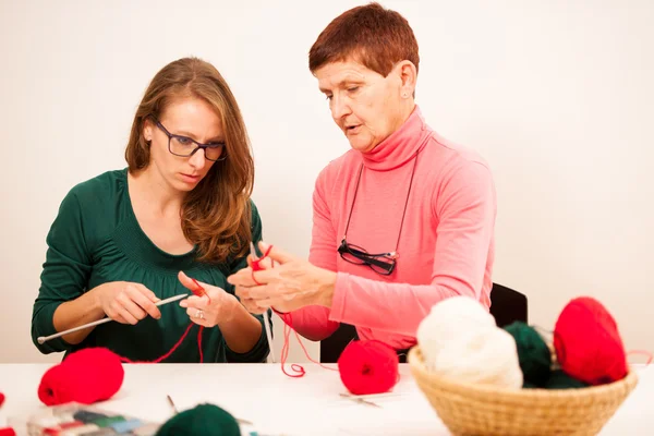 Women knitting with red wool. Eldery woman transfering her knowl