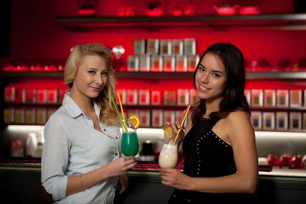 Two beautiful women drinking cocktail in a night club and having