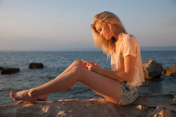 Beautiful young blonde woman resting on a beach at dusk in early
