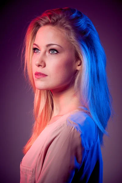 Beauty portrait of young blonde woman with red and blue light on hair