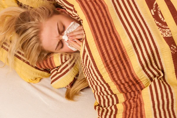 Sick woman lying in bed covered with blanket, feeling ill, has f