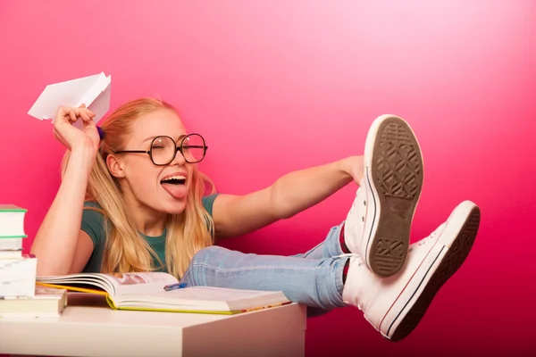 Playful, naughty schoolgirl with big eyeglasses throwing paper a