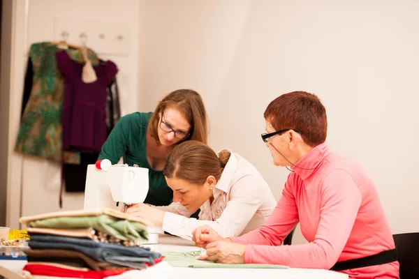 Three women are sewing on handcraft workshop. They are teaching