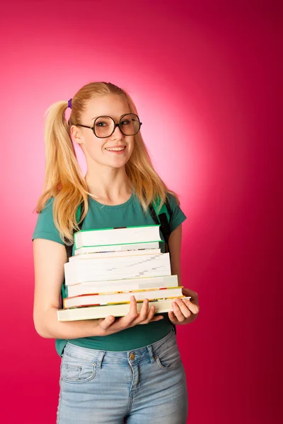 Curious, naughty, playful schoolgirl with stack of books and big