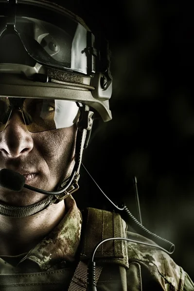 Military man in camouflage wearing helmet, glasses, radio set