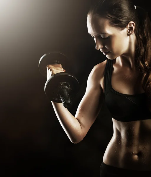 Fitness muscular woman working out with dumbbells