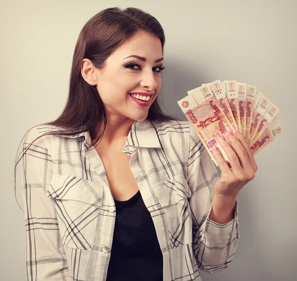 Happy young casual woman holding rubles with toothy smiling. Ton