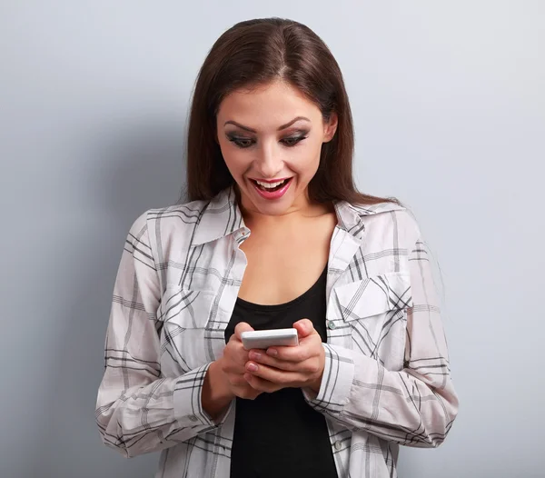 Happy surprising woman looking in mobile phone and reading sms w