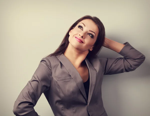 Successful thinking woman in suit looking up and scratching the