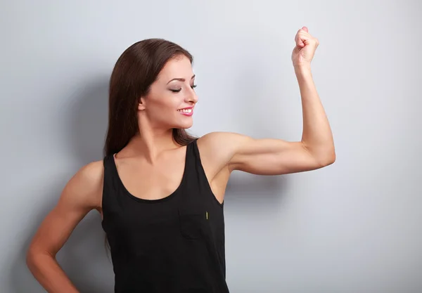 Strong fitness young woman showing muscle bicep with happy smili