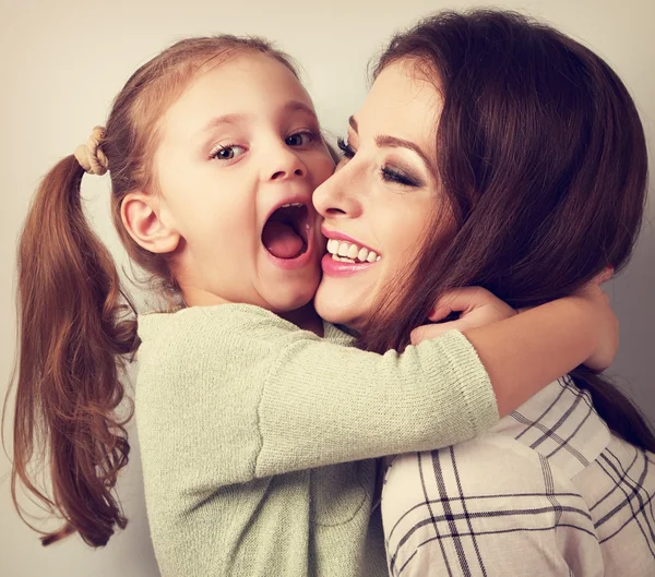 Happy grimacing kid wanting to biting her laughing mother in nos