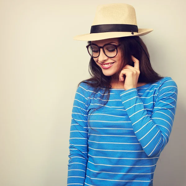 Fun young thinking woman looking down in glasses and straw hat.