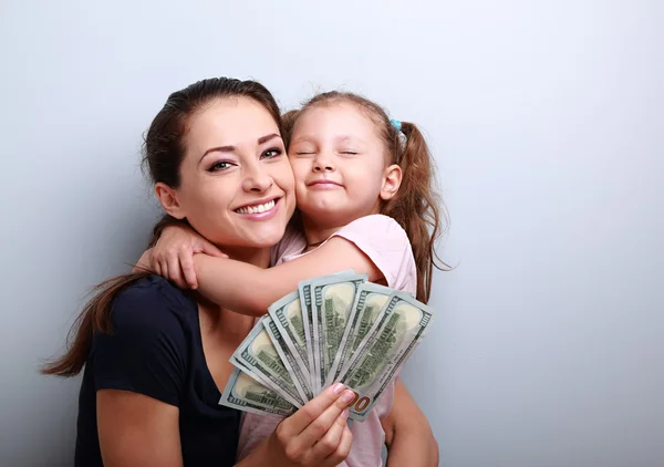 Smiling mother and happy cute daughter hugging and showing dolla