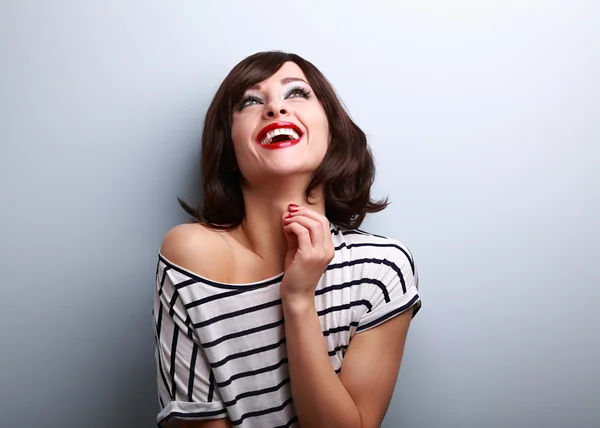 Happy natural toothy laughing young woman looking up