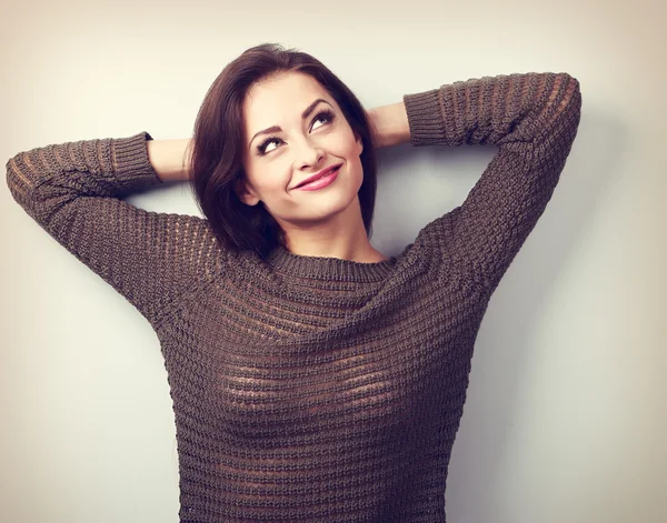 Smiling thinking casual woman in warm sweater looking up with ha